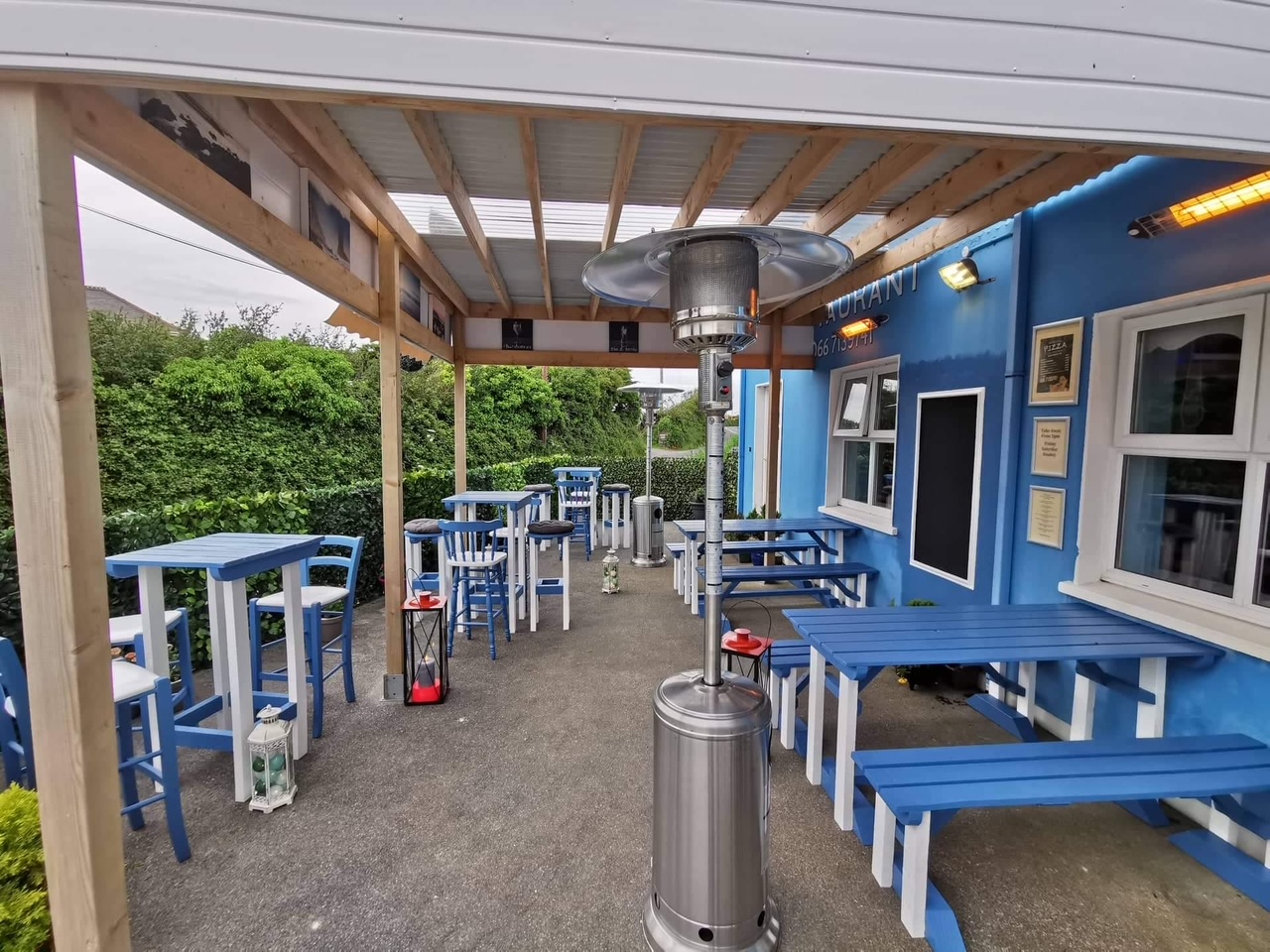 Covered outdoor terrace with blue picnic benches and patio heaters