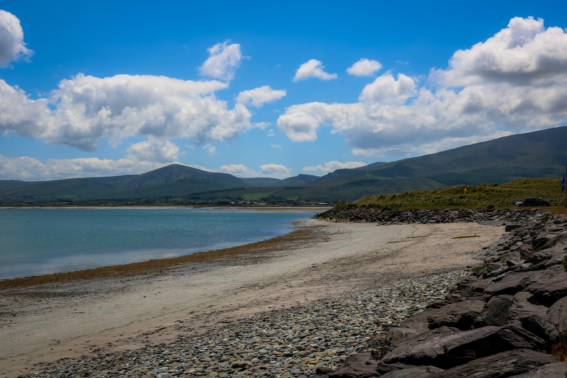 Curved shoreline of Castlegregory Beach with mountains across the bay