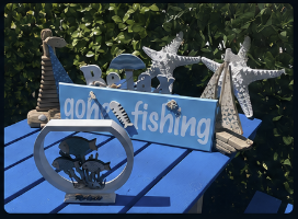 Hand-painted 'Gone Fishing' sign with starfish and coastal ornaments outside Pisces